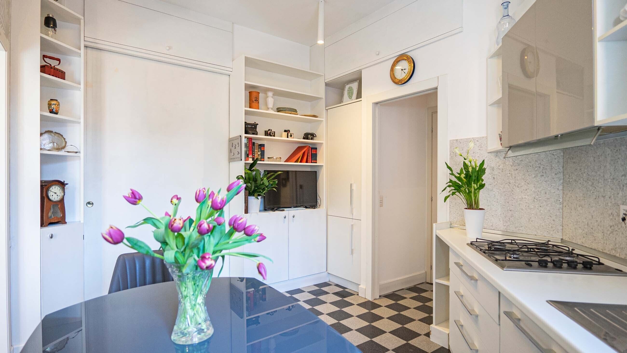 Una cocina moderna con estufa a gas, alacenas blancas y piso a cuadros.