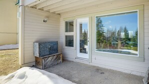 A covered porch with a large window and a small door, a wooden bench, and a metal cabinet. - Picturesque Mt Spokane Condo Near Skiing & Biking! (Mead)
