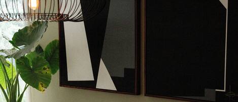 A modern dining area with a wooden table, grey chairs, a hanging light fixture, and abstract wall art.
