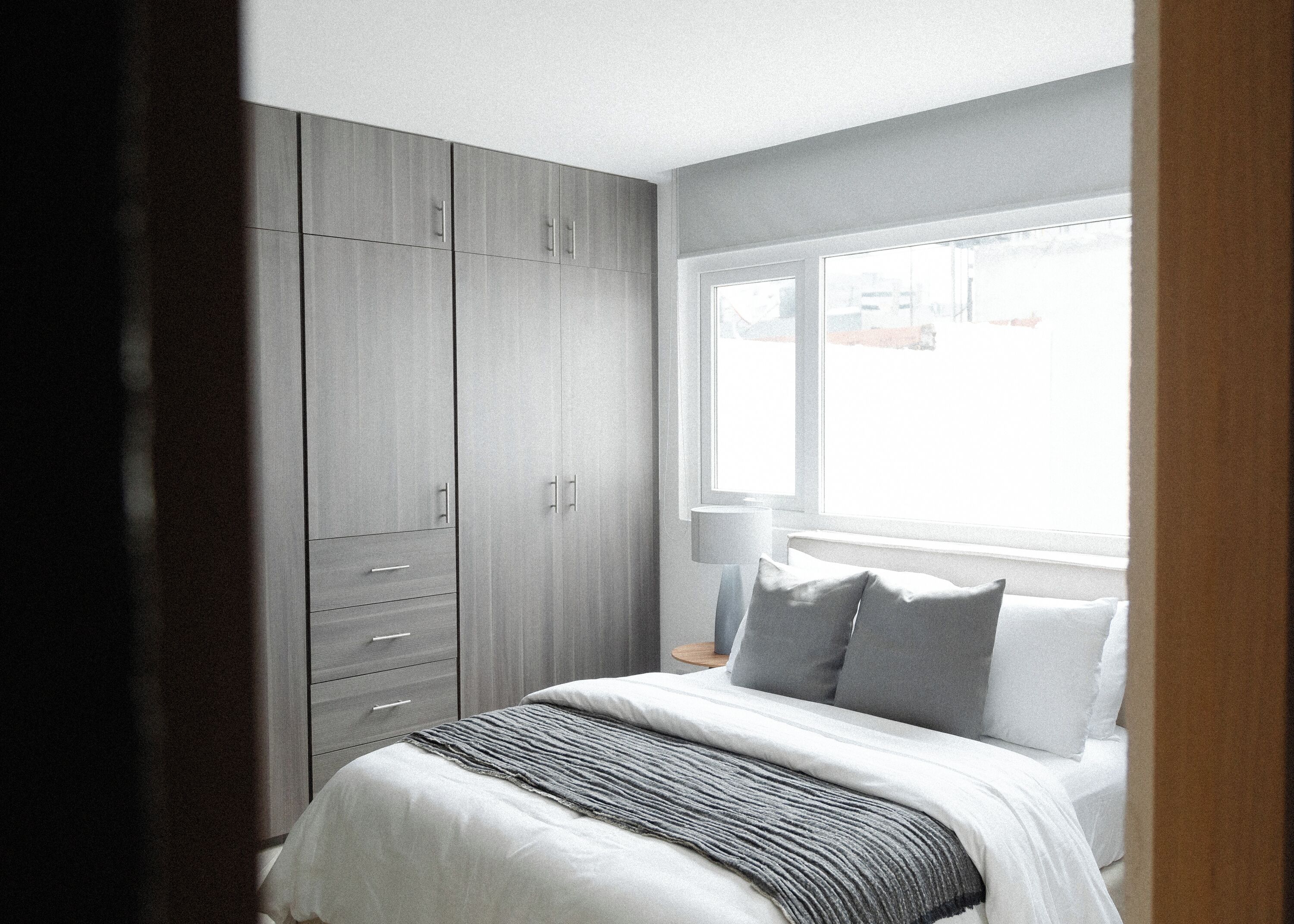 A bedroom with a bed, a window, and a wardrobe.
