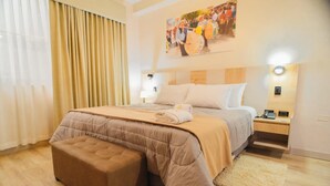 A hotel room with a large bed, a bedside table with a lamp, a wooden headboard, and a painting on the wall. - Sauna & Suite Puñuykuna (Cajamarca)