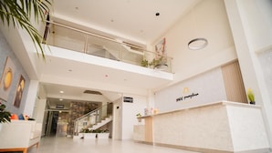 A hotel lobby with a reception desk, a staircase, and a glass railing on the upper level. - Sauna & Suite Puñuykuna (Cajamarca)