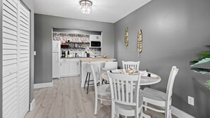 Une cuisine moderne avec des meubles blancs, un îlot central et un coin repas avec des chaises blanches.