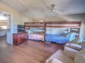 Habitación pequeña con literas, un televisor, cómoda de madera y ventilador de techo.