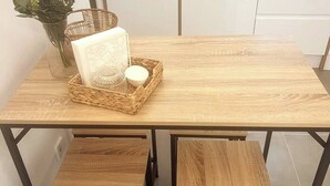 Une table en bois sur laquelle repose un panier tressé contenant une bougie et une carte.