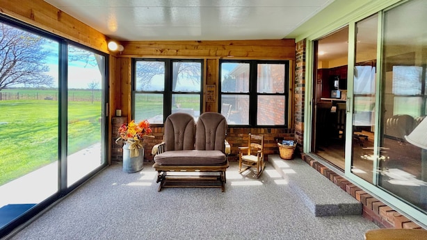 A cozy room with a large window, a comfortable chair, a small table, and a vase with flowers.