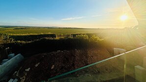 Un paisaje rural con cielo despejado y el sol bajo en el horizonte.