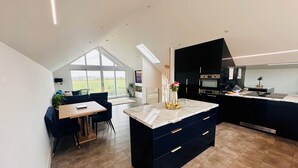 Una cocina moderna con armarios oscuros, encimera de mármol y vistas al exterior.