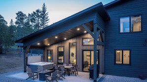 Een modern huis met een overdekte patio, buitenmeubels en een jacuzzi.