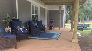 Ein überdachter Patio-Bereich mit Korbmöbeln und einem roten Rasenmäher.