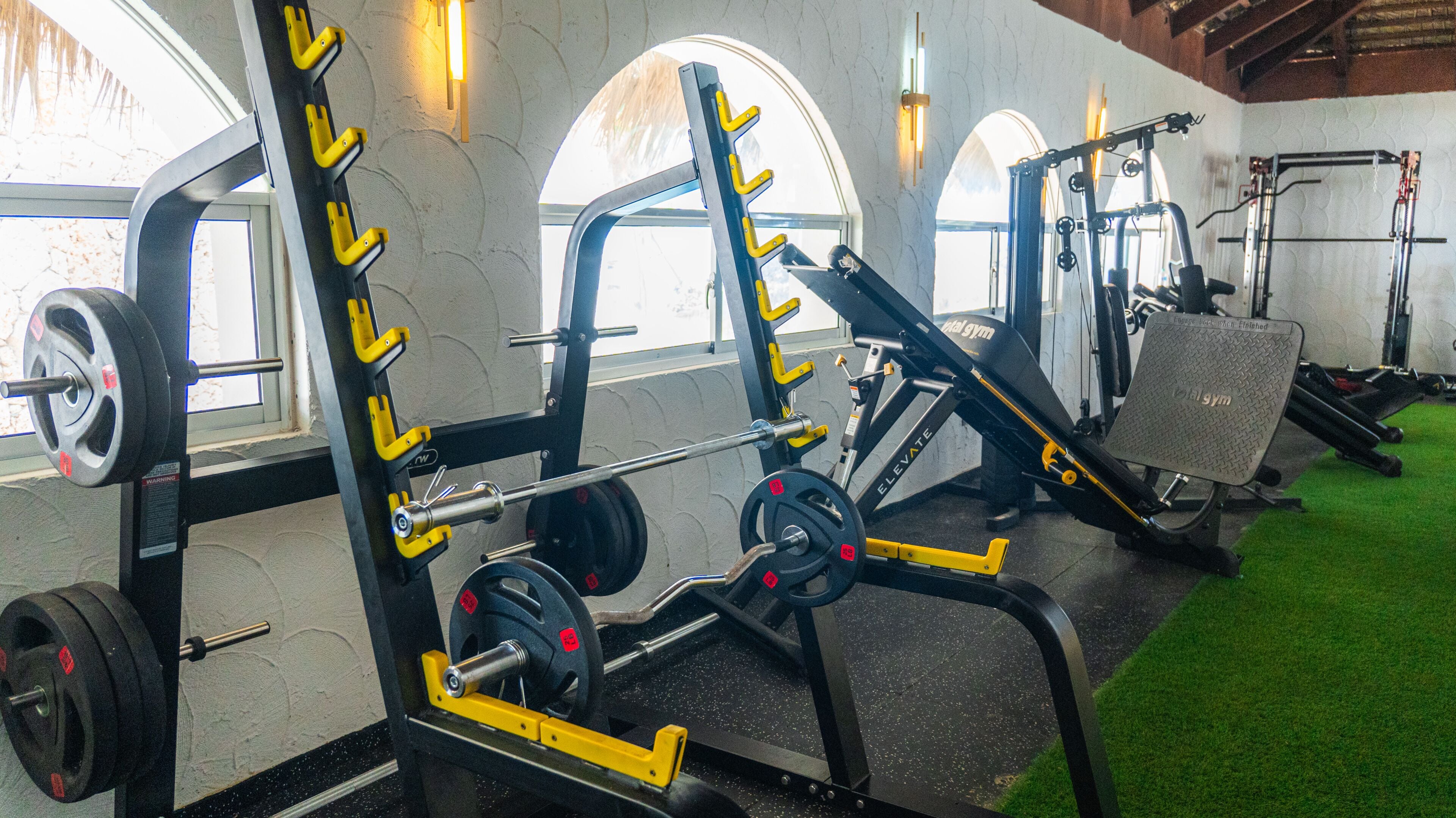 A gym with weightlifting equipment, including a squat rack and benches.