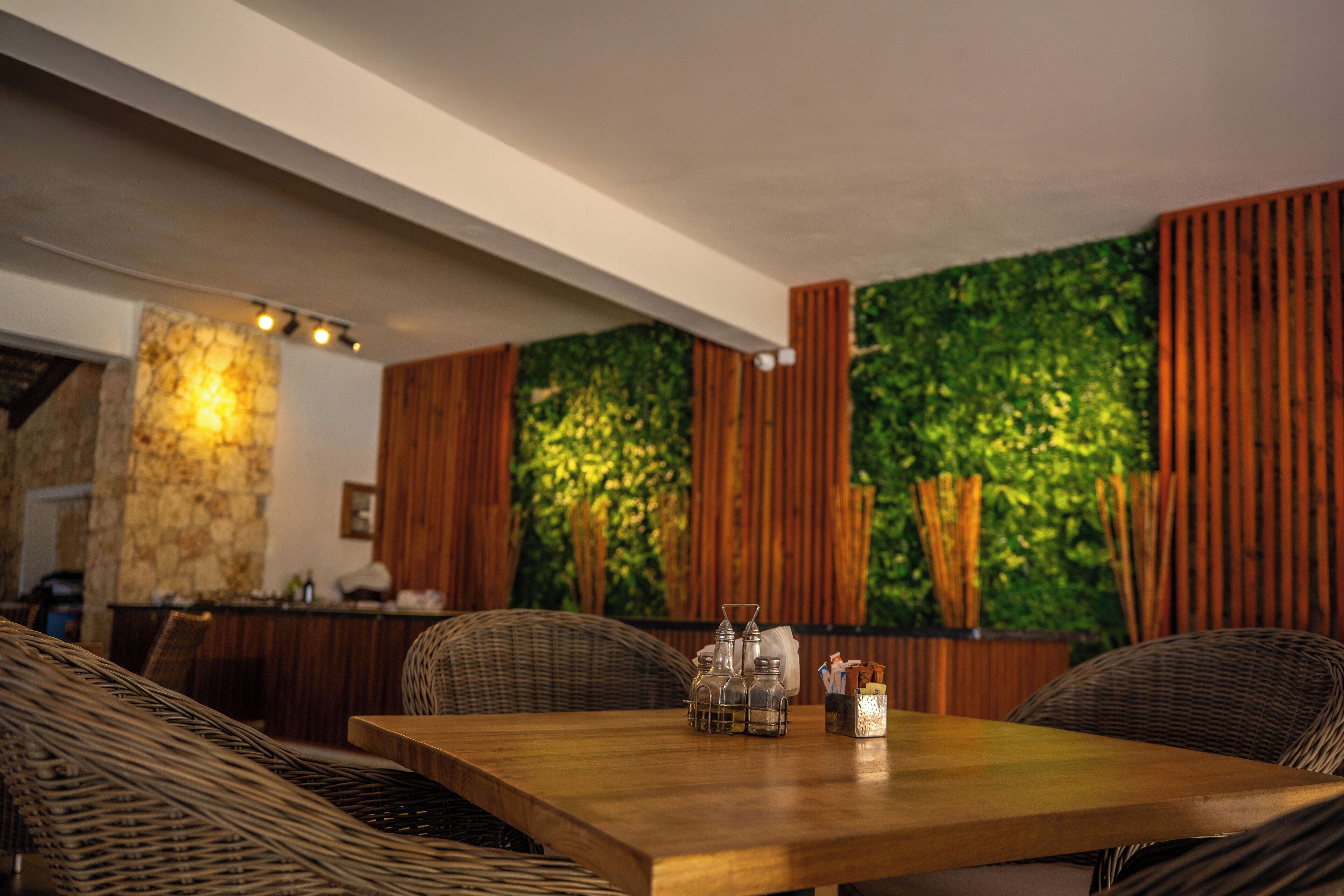 A dining area with a wooden table, wicker chairs, a stone accent wall, and vertical wooden slats.