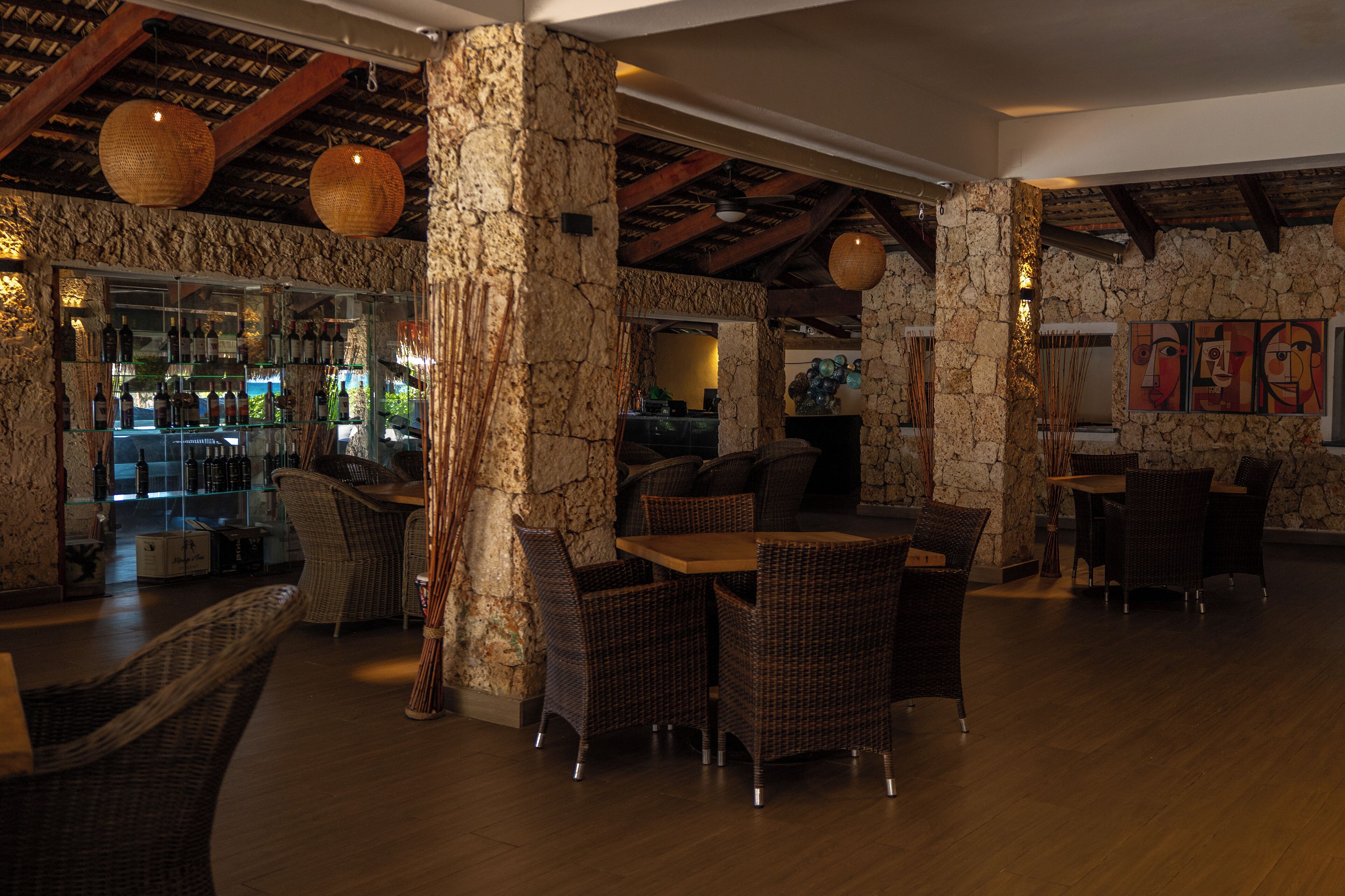 Un restaurante con paredes de piedra, muebles de mimbre e iluminación colgante.