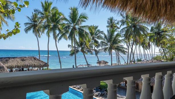 Blick auf einen Pool mit freiem Blick auf das Meer und Palmen.