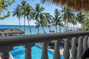 A poolside view with a clear view of the ocean and palm trees. - TRIBE BOUTIQUE RESORT By Mega Stays (Guayacanes)