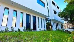A modern white building with multiple windows and a flat roof. - Hotel La Casona San Sebastian  (Puerto Triunfo)