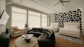 A modern bedroom with a curved black sofa, a white bed, and a ceiling fan.