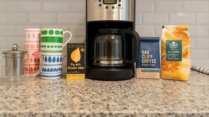 Une machine à café, une boîte de capsules de café et un récipient de café moulu sur un plan de travail de cuisine.
