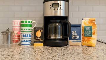 A coffee maker, a box of coffee pods, and a container of coffee grounds on a kitchen counter.