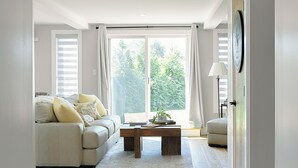 A modern living room with a sofa, a coffee table, and a large window. - Scenic 4BR/3BA Waterfront Getaway with private dock, kayaks & Stunning Views (Dartmouth)