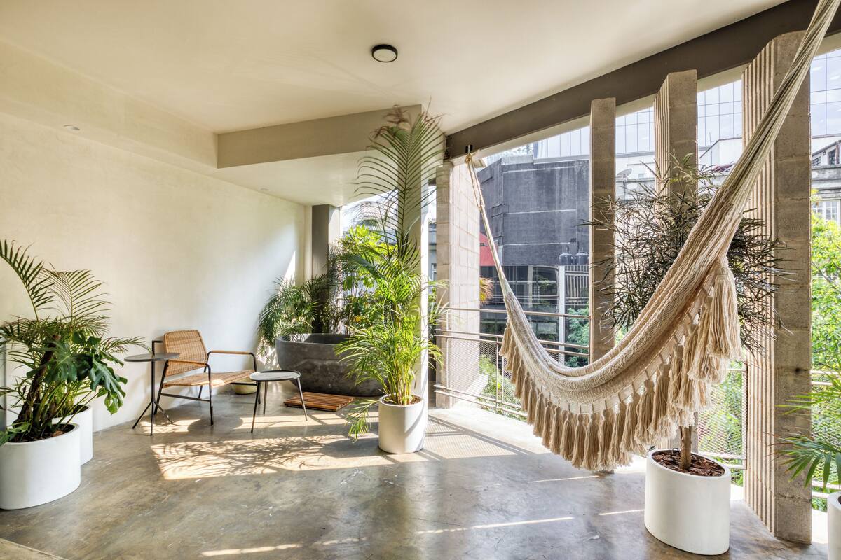 Ein geräumiger Balkon mit einer Hängematte, Topfpflanzen und einer Sitzecke mit Stuhl und Tisch.