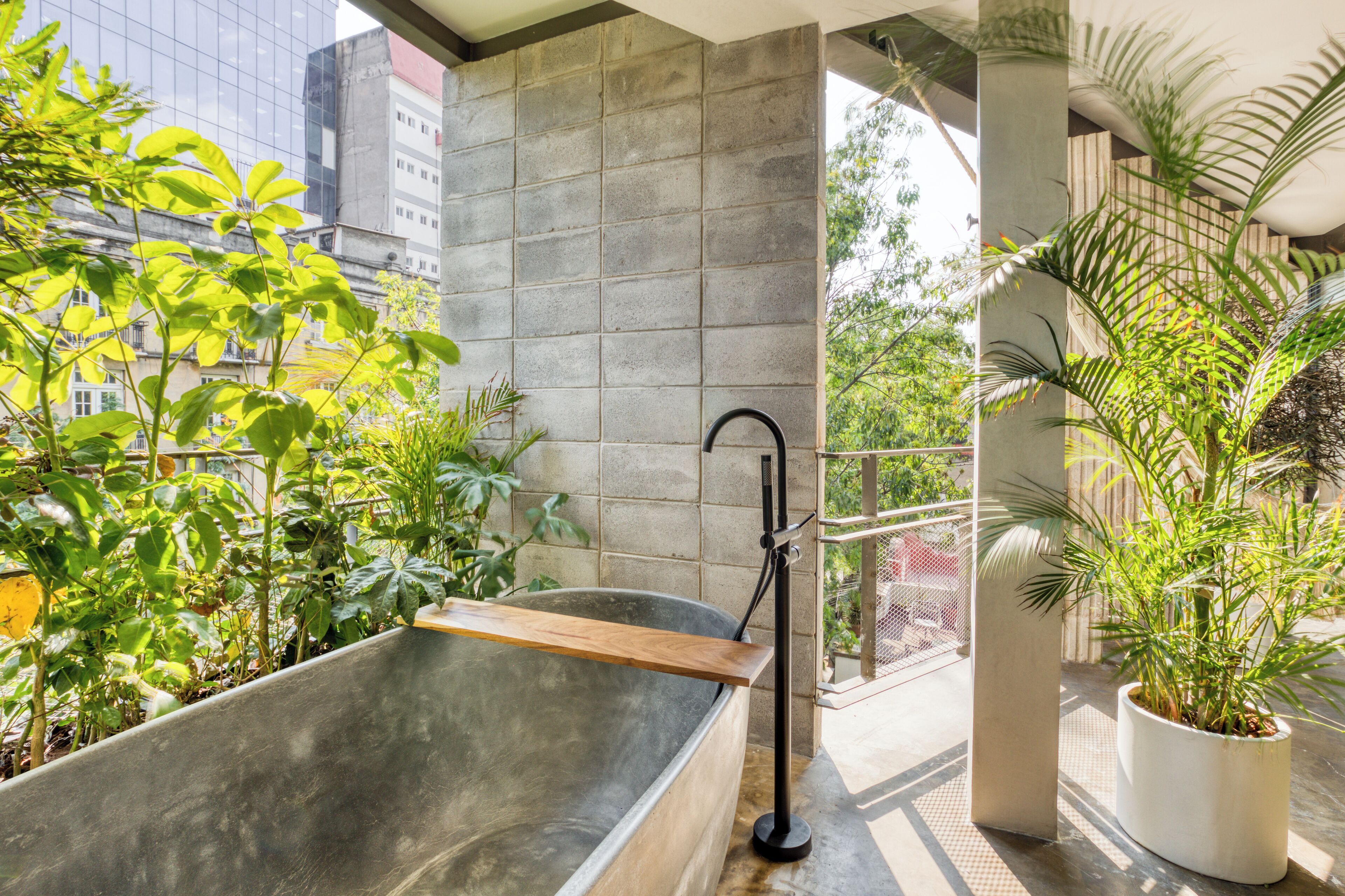 Un baño moderno con una bañera grande, un estante de madera y una planta en maceta.