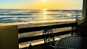 Uitzicht op het strand vanaf een balkon met een tafel en stoelen.