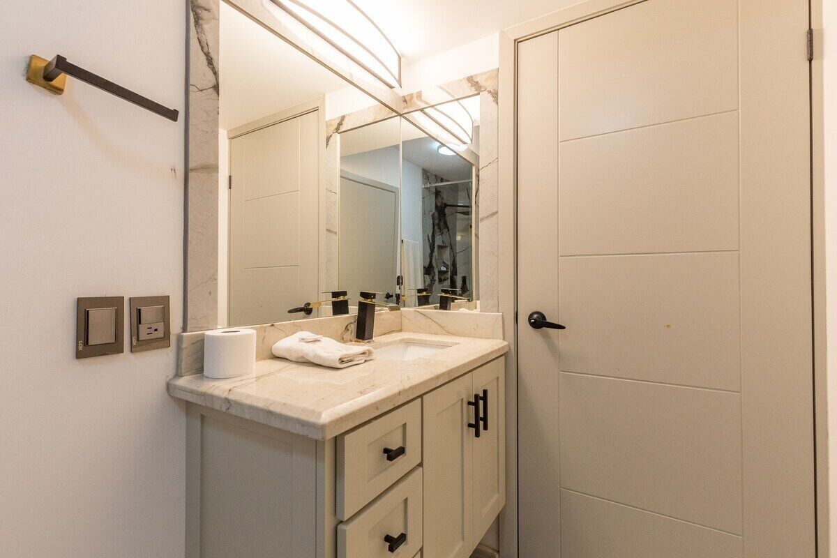 Un bagno con un lavabo in marmo, uno specchio grande, un asciugamano e una porta.