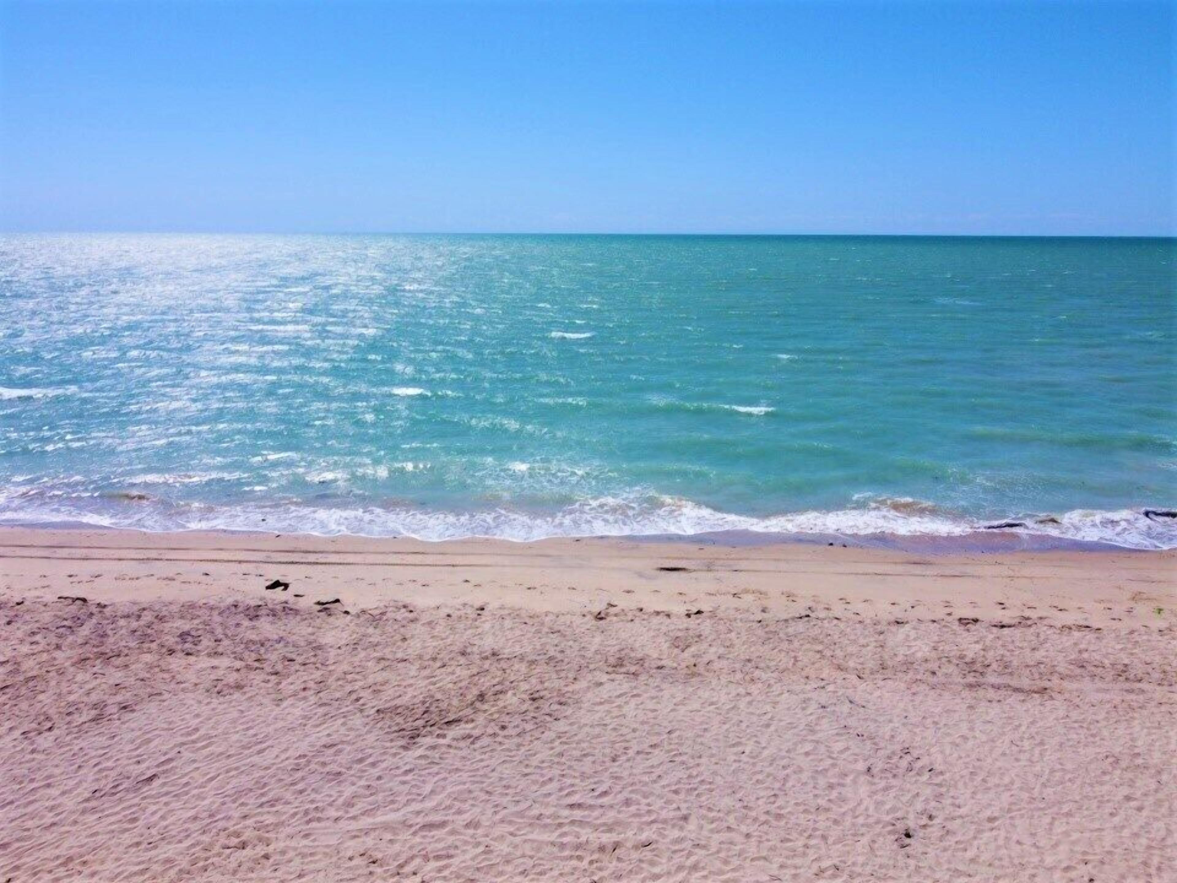 A beach with clear turquoise water and a sandy shore.