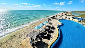 Een strand met een zwembad, ligbedden en parasols.