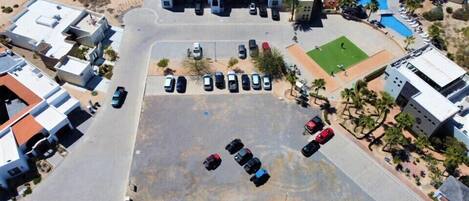 An aerial view of a resort with a swimming pool, multiple buildings, and a parking lot.
