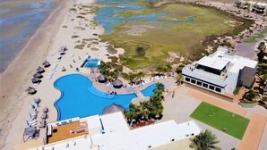 Luchtbeeld van een resort met een groot zwembad, een strandgedeelte en een golfbaan.