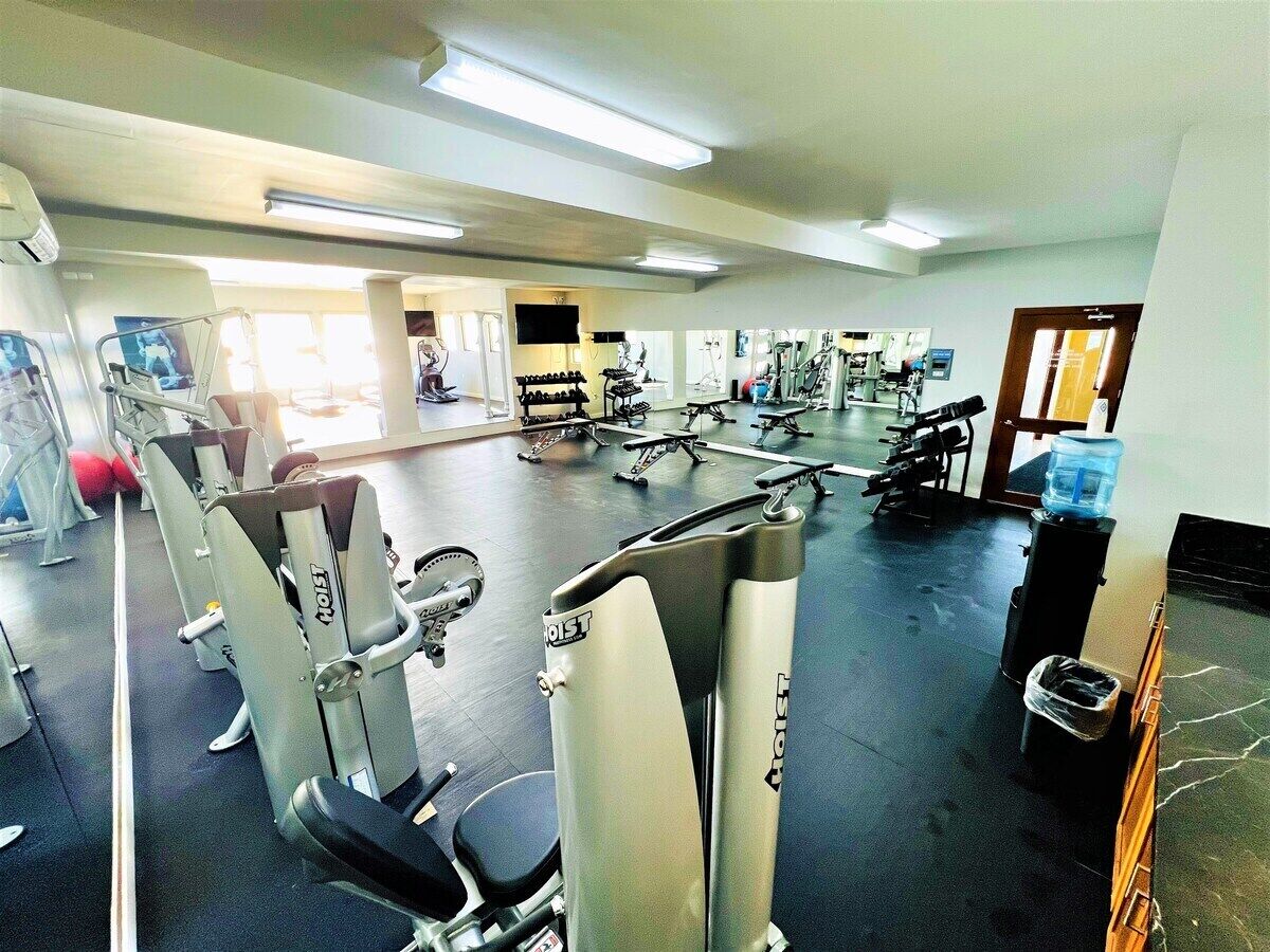 A gym with various exercise machines, a water dispenser, and a trash bin.