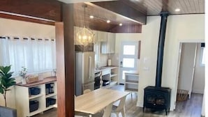 A modern kitchen with white cabinets, a wooden dining table, and a black stove. - Lakeside Cottage Getaway South Shore Lake Scugog

 (Caesarea)