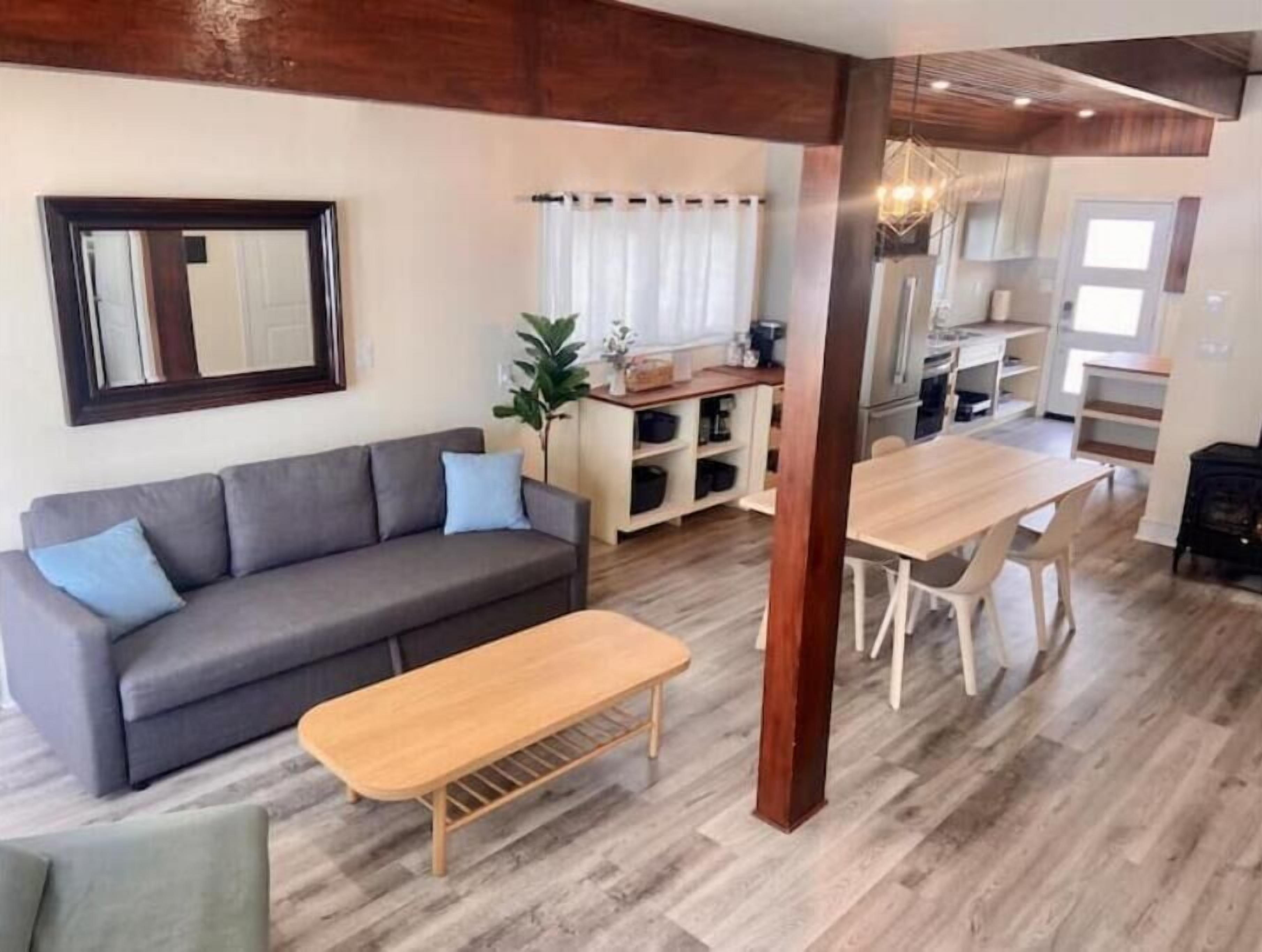 Un salon moderne avec un canapé, une table basse en bois et un coin repas comprenant une table et des chaises.