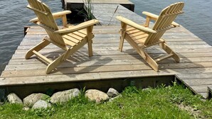 A wooden dock with two Adirondack chairs facing a calm lake. - Cozy Lakeside Cottage on Lake Scugog

 (Little Britain)