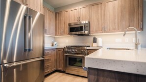 A modern kitchen with stainless steel appliances, wooden cabinets, and a granite countertop.