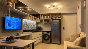 A compact kitchen with a TV, washing machine, and a refrigerator.