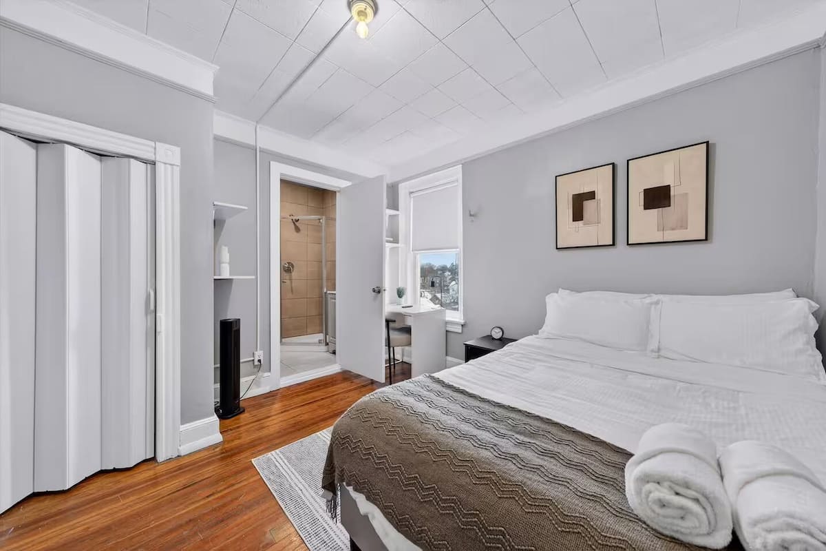 Quarto com cama, closet espaçoso, chuveiro e vista para a cidade.