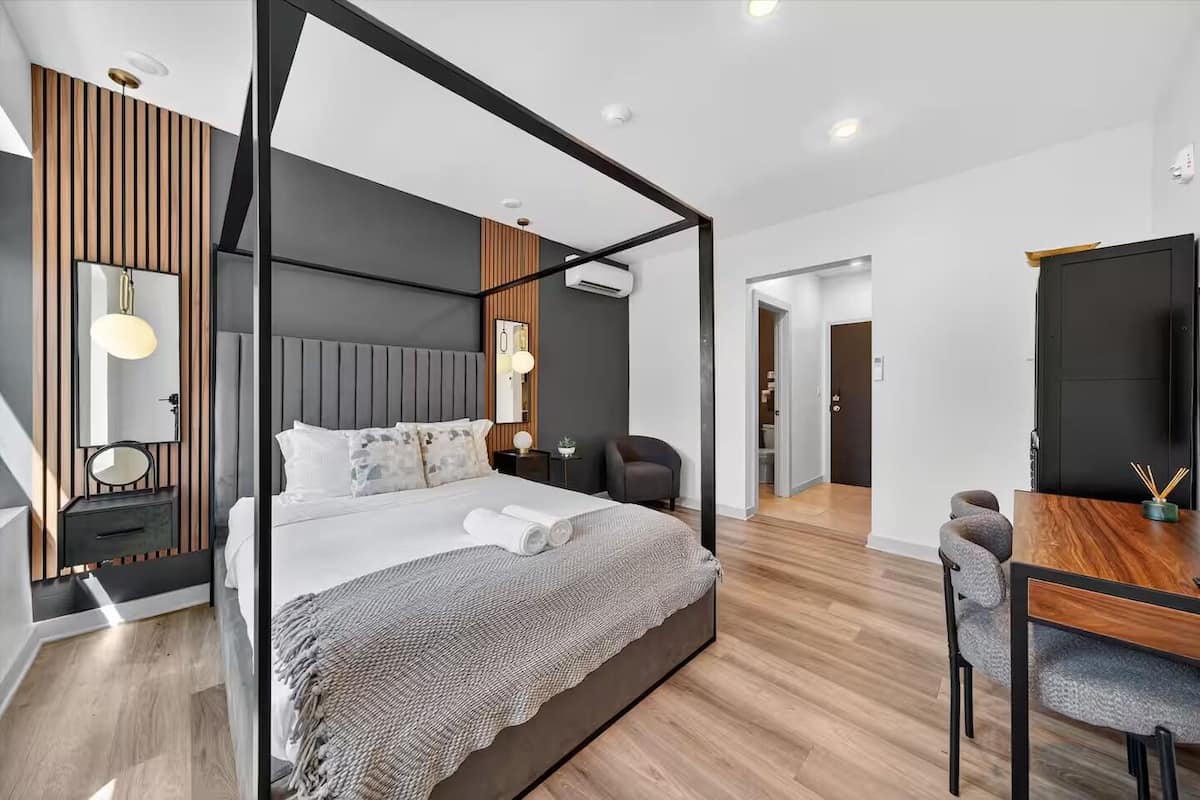 Quarto moderno com cama de dossel, escrivaninha e uma cadeira.