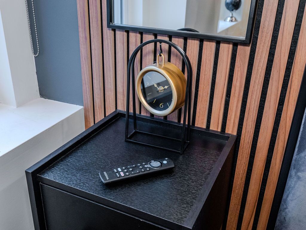 A small black table with a round clock and a remote control on it.