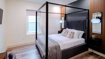 Un dormitorio moderno con cama con dosel, una mesita de noche, un espejo y una ventana.