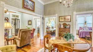 A spacious living room with a wooden floor, a dining table, and a chandelier.