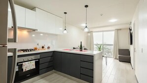 A modern kitchen with a central island, stainless steel appliances, and pendant lighting. - Ocean VIEW, Pool&Coworking, Queen Bed 19th floor (Barranco)