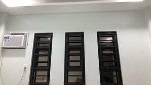 A room with three black-framed windows and an air conditioning unit mounted on the wall. - We provide transport going to shopping center, restaurants and tourism office. (Donsol)