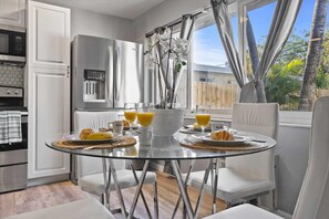 Enjoy breakfast at the glass dining table, set with fresh fruit, croissants, and orange juice.