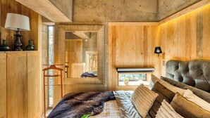 A bedroom with a large bed, wooden walls, a mirror, and a hanging light fixture. - SAN LUIS POTOSI by Mr. W (Mexico City)