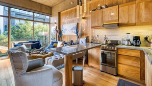 A modern kitchen with wooden cabinets, a central island, stainless steel appliances, and a large window offering a view of greenery. - SAN LUIS POTOSI by Mr. W (Mexico City)