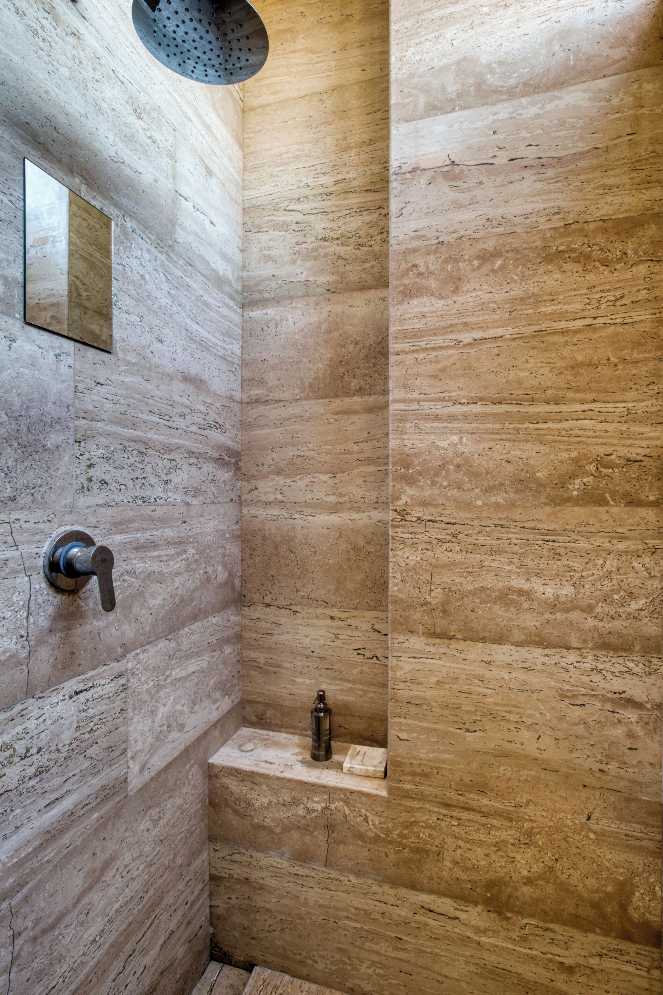 A modern bathroom with a stone wall, a built-in sink, and a showerhead.