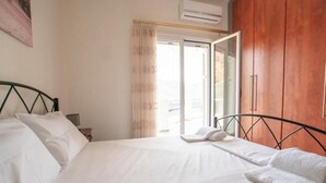 Een hotelkamer met een bed, nachtkastje, kledingkast en raam met gordijnen.
